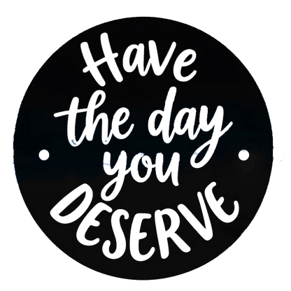 Round black decal with white and black script lettering that reads “Have the day you deserve,” with two small white mounting dots on the sides.